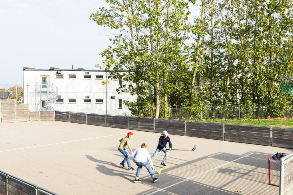 Tingdalsskolans exteriör med delar av skolgården och en fotbollsplan i förgrunden.